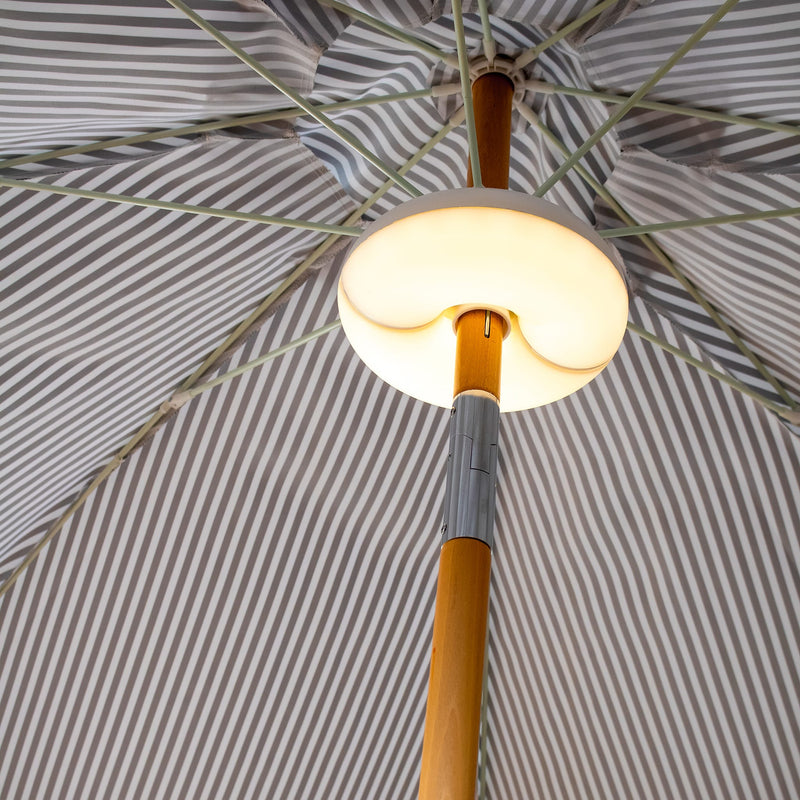 Lima cordless lamp by Newgarden attached to a patio umbrella, providing elegant and adjustable outdoor LED lighting.